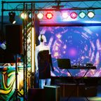 Club with mixing station and lights, audio sound panel on stage used for dj at disco party with funky music. Empty dance floor at discotheque, fun live performance at nightclub. Handheld shot.