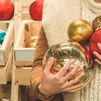 Girl in a warm coat holding large ball for Christmas tree in a mall at the Christmas Fair. Winter mood