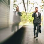 Handsome young businessman with mobile phone by the office building
